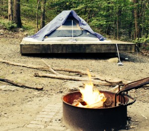 Blue tent on elevate platform with open campfire